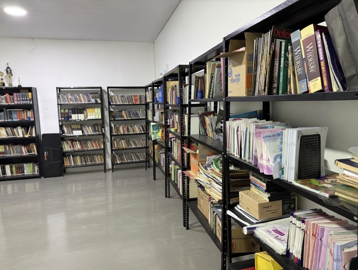 Biblioteca da Igreja Batista Manancial — estantes com livros, revistas e materiais didáticos